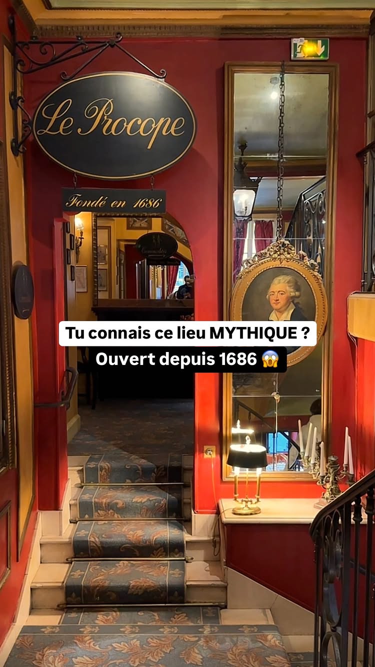 The image shows the interior of a grand, historic restaurant. The entrance is defined by a set of stairs with blue carpet, red walls, and golden accents. A sign for Le Procope and a banner reading 'Fondé en 1686' are visible, confirming the restaurant's age. A mirror and a portrait add to the classic aesthetic. Overlaid text reads 'Tu connais ce lieu MYTHIQUE ? Ouvert depuis 1686 😱'.