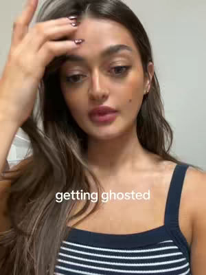 A female wearing a striped tank top, with a hand touching her hair looking directly at the camera with text overlayed.