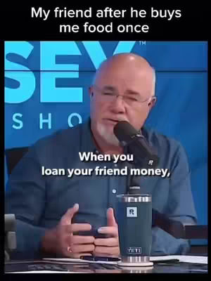 A man wearing a blue shirt is speaking into a microphone. Behind him is a blurred image of a show's logo.