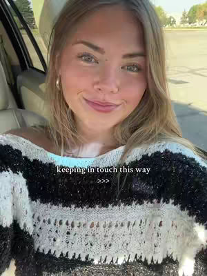 A young woman is sitting in a car seat, smiling and looking at the camera. She is wearing a black and white striped sweater and has blonde hair. Text overlay at the bottom reads, 'keeping in touch this way' with arrows.