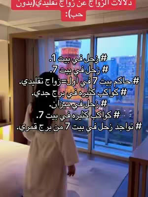 A person stands in a room with a large window overlooking a city. The person is wearing a white robe.