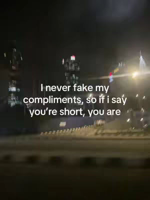 An out-of-focus, night-time urban scene with blurred lights and indistinct buildings, conveying a sense of movement as if viewed from a moving vehicle. Overlayed text in white conveys a lighthearted message.