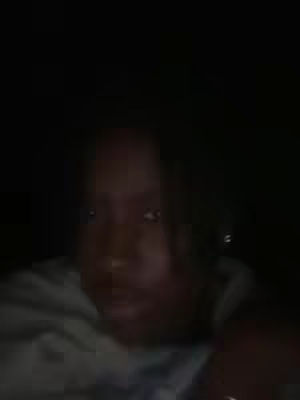 A dimly lit selfie shows a person in shadow, with the face as the main focus. The image is primarily dark, with faint details of the person's face and a light-colored garment.