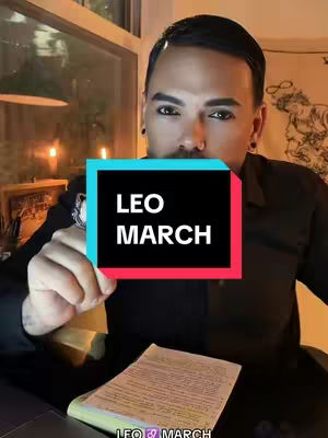 A man with dark features poses with a sign, set against a backdrop of a bright window and warm lighting. The sign reads "LEO MARCH" as an overlay.