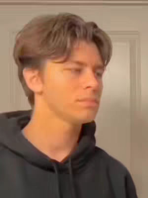 The cover image features a young man in a black hoodie, looking off to the side with a neutral expression. The background is a plain, light-colored wall and doorframe, focusing attention on the subject.