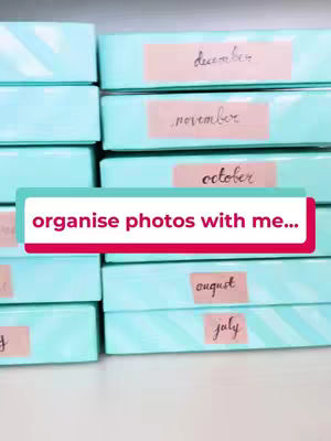 The cover image shows a stack of light blue boxes, likely storage boxes, with pink labels on them. The labels have handwritten text for each month, starting with december, november, october, august, and july. A text overlay in a pink background with white text that says "organise photos with me..." at the center.