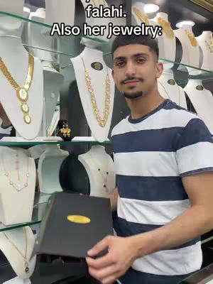 A man in a striped shirt stands in a jewelry store holding a box. Behind him are displays of jewelry, including necklaces.