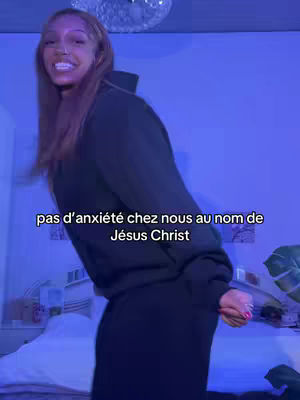 A young woman in a black hoodie and sweatpants stands in a room with a bed at the background. She appears to be smiling, and text is overlaid on the bottom.