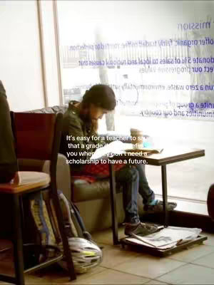 The image shows a person studying at a table in a cafe setting. The person is wearing a jacket and seated, with a backpack and other items visible. A text overlay conveys a sentiment about education and scholarships.