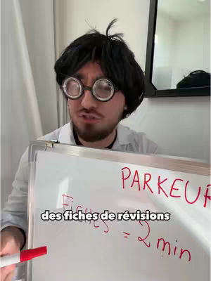 A person in a wig, large round glasses, and a lab coat holds a whiteboard with handwritten text and a red marker. Behind them, a mirror and part of a wall are visible.