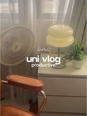 The cover image shows a well-lit interior scene featuring a white table with a lamp, a small plant, and a stylized chair with tan cushions. The words "uni vlog" and "productive" are layered on top.