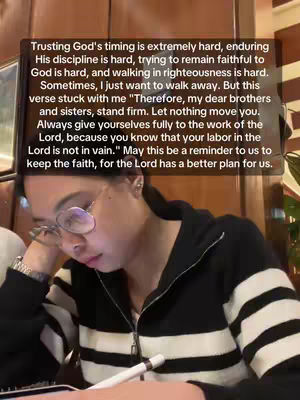 A woman with glasses looks pensively down at an open notebook and pen. The image features a text overlay with a quote about faith and perseverance.