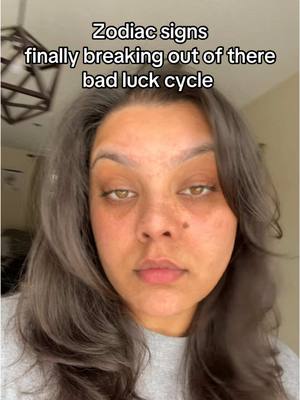 The cover image shows a close-up of a woman's face. The background is slightly blurred, but appears to be an indoor setting with a light fixture visible. The text overlay states, "Zodiac signs finally breaking out of there bad luck cycle."