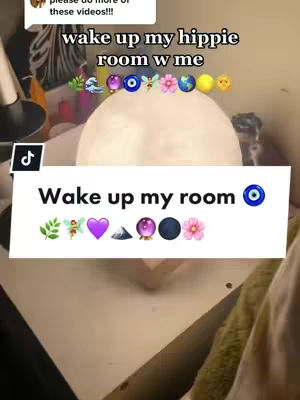 The image features a close-up view of a room, likely a bedroom, with a large, round, white light fixture resembling a moon as the focal point. Below this light, a white box with text overlayed contains the phrase "Wake up my room," along with several colorful emojis like leaves, a fairy, hearts, a mountain, a crystal ball, and flowers. The background reveals a portion of a desk or surface, with soft lighting and a neutral color palette. The composition is simple, drawing the viewer's attention to the text and emojis.