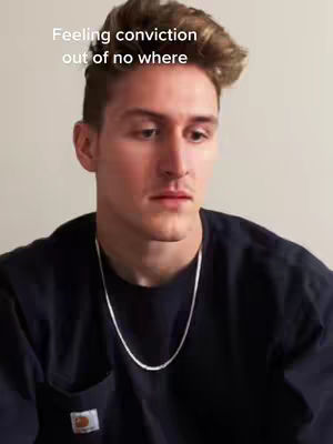 The cover image is a medium shot of a fair-skinned person with light brown hair and a black t-shirt. The person is looking down with a serious expression with a silver necklace. The background is a plain, light-colored wall.