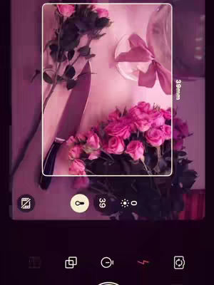The cover image showcases a close-up shot taken through a smartphone app, focusing on a combination of objects within a pink-hued setting. A bouquet of pink roses appears prominently, alongside a large knife placed near the flowers, suggesting a juxtaposition of beauty and potential danger. Additionally, a small, open gift box adorned with a pink ribbon is placed on what appears to be a reflective surface. The composition is framed by a white rectangle, a filter effect has been applied to the image, giving the picture a dreamy, atmospheric quality, and the overall color palette maintains a consistent tone of pink and violet.