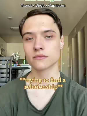A young man with light skin and dark hair looks directly at the camera. Above his head are the words 'Air Signs' and below him is the text: trying to find a relationship. His shirt is green and there is an interior background, with a hint of a kitchen and what looks like a dining table in the background.