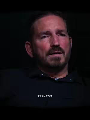 A medium shot features a man with brown hair and a beard looking slightly to the side. The background is dark, emphasizing the man's face and upper body, and at the bottom center, the website pray.com is visible in white text. The overall tone is serious and focused.