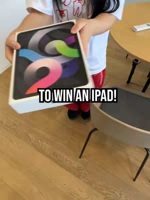 A person is holding the box of an iPad. The image is shot from above with the person holding the box towards the viewer and the text overlayed is written in black text that says 'TO WIN AN IPAD!'