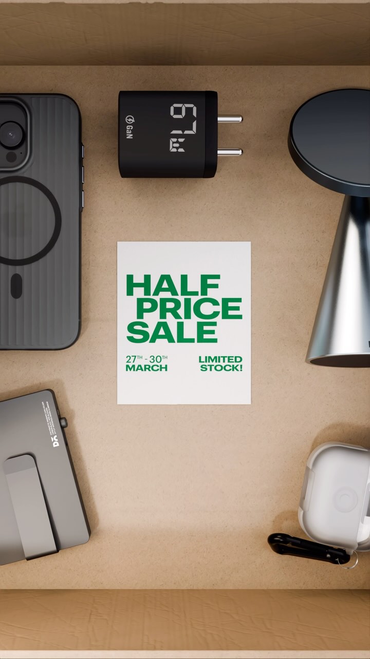 A top-down shot presents tech gadgets neatly arranged in a wooden drawer, centered around a white card with green text advertising a 'Half Price Sale' from March 27th-30th. The items include a black phone case, a charging device with a digital display showing '67', a silver stand, a tablet-like device, and a pair of white wireless earbuds, all set against a warm, neutral background with subtle shadows.