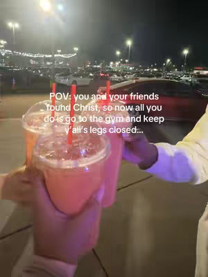The image shows three clear plastic drink cups held up in a celebratory toast. The drinks appear to be pink or red, and have straws in them. The cups are in the foreground, with hands holding them. In the background are cars parked in a lot and a dark night sky. Text is overlaid on the image.