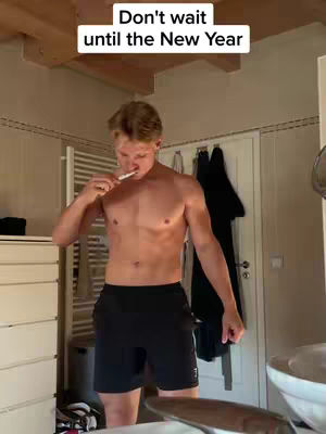 A shirtless man brushes his teeth in a bathroom. A text overlay says, "Don't wait until the New Year".