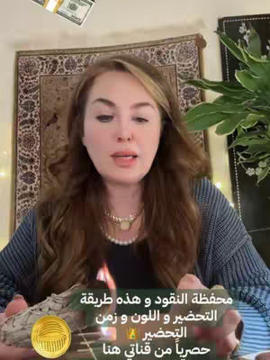 A woman with long brown hair sits facing the camera. She holds a lit bundle of incense in her hands. Dollar bills appear to float above her head which is against the background of a tapestry and some plants.