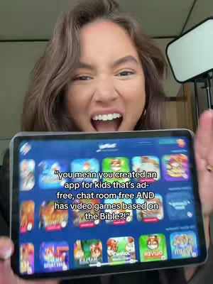 A woman with brown hair is holding a tablet displaying an app filled with colorful cartoon game icons. Her mouth is wide open in an excited expression.