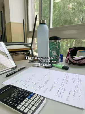 The cover image features a desk in a classroom setting with a variety of study materials. A calculator sits in the foreground next to a paper covered in equations. A water bottle, a cup, a pen, and a highlighter are on the desk. Behind the desk, a window provides a view of the outdoors.