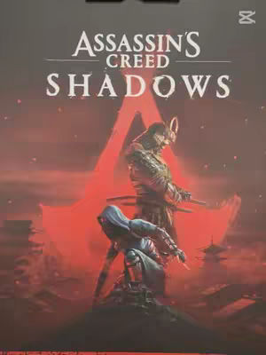 The cover image is an advertisement for Assassin's Creed Shadows game, featuring two characters in a red-hued landscape. The background features a large red emblem, possibly the game's logo. Two figures are in the foreground, one standing with a long sword and the other kneeling. The color palette is dominated by reds and dark tones, creating a mysterious, action-oriented and epic atmosphere.