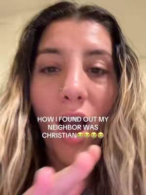 A close-up selfie shows a young woman with long, wavy blonde and dark-brown hair. She's looking at the camera, with text overlaid that reads, "HOW I FOUND OUT MY NEIGHBOR WAS CHRISTIAN" with emoji faces below. The woman is pointing forward with her right index finger, emphasizing the message. The background is plain.