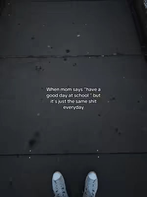 A top-down shot shows a dark gray surface, possibly a walkway or pavement, with text towards the center. Two light-colored sneakers are visible at the bottom of the frame.