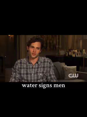 A man with brown hair and a plaid shirt is sitting and looking at the camera. Text at the bottom of the image reads: "water signs men". The background is dim and appears to be indoors.