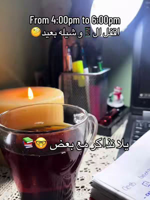 A dimly lit study scene, featuring a cup of tea with a book and glasses emoji on the glass, a lit candle, a laptop, and various stationery items in the background. The image is warm-toned.