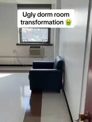 The image shows a dorm room setting. In the foreground, there is a black leather armchair. The room has white walls, a large window, and a small air conditioning unit beneath the window. There's a title overlay on the top part of the image.