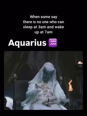 The image features text overlaid on a dark background, with a still from what appears to be a movie or television show. At the top, white text reads 'When some say there is no one who can sleep at 3am and wake up at 7am'. Below this, the word 'Aquarius' is written in a larger, bolder, white font, accompanied by a purple zodiac symbol. The image in the background depicts a statue of a person wearing a hooded robe, holding an open book. The statue has a green-tinted complexion, suggesting it is carved from stone or a similar material. The setting is dark and appears to include flames located to the right of the statue.