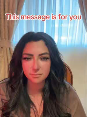 A woman with long black hair and makeup looks directly at the camera, set against a backdrop of drapes and a window. Red lighting accents the scene, and text at the top reads, 'This message is for you.'