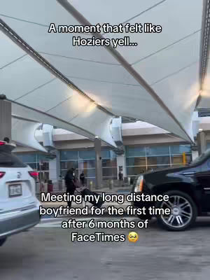 An outdoor scene at an airport or similar covered area, likely during the daytime. The main focus includes a car parked to the right and another to the left. In the background, there are some people walking, the sky peeking into the image. The text is in the upper and middle areas of the image and is likely user-added content. The overall tone is a snapshot of a time of excitement or nostalgia.