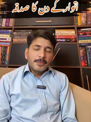 A man with a mustache and a collared shirt sits in front of a bookshelf filled with books. Overlayed text at the top of the image is in a non-English script.