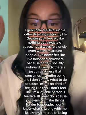 A person with dark hair and glasses is centered in the frame, with text overlaid on their face. The background is a soft, neutral tone, and the person's expression is serious.
