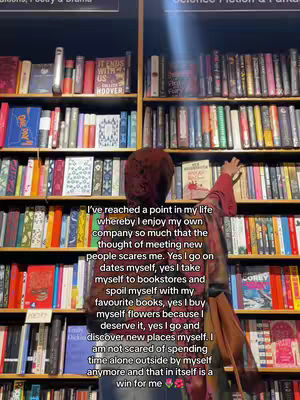 The image is a selfie of a person in front of a library bookshelf. The person has auburn hair and is wearing a maroon jacket. The background is filled with books, creating a cozy and intellectual atmosphere. Overlay text is added to express sentiment.