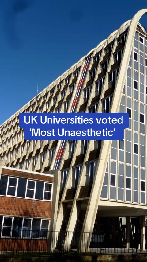 The image features a large, multi-story university building with a distinctive architectural design, characterized by a series of sloping facade elements and arched top. The building's facade has a patterned interplay of dark and light sections, and light-colored supports frame the front and the facade with a blue sky background.
