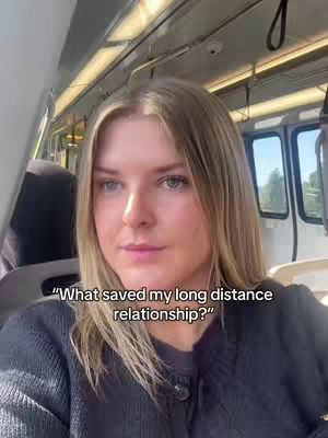 A woman with blonde hair is sitting inside a train. The image is slightly angled, and the train interior is visible with seats and windows in the background. Text overlayed on the image asks a question about what saved her long-distance relationship.