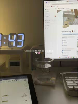 The cover image shows a well-lit workspace with a digital clock displaying 1:43. A computer monitor displays a webpage. A clear cup sits in the center on the desk. An iPad and a mechanical keyboard are also on the desk. The text overlay is "Comment to stay on studybreak."