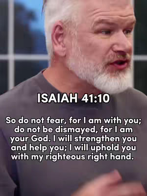 A medium shot of a man with gray hair and a beard, wearing a gray shirt. Text overlays the image, including the Bible verse in the bottom third of the image.