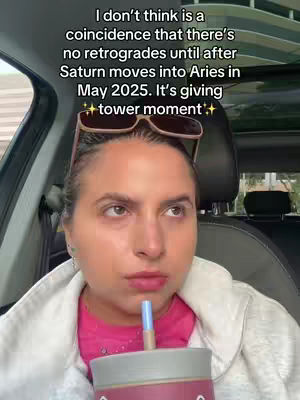 A woman inside a car stares intensely towards the camera, holding a drink with a straw. Over her head are sunglasses perched on her head, and a text overlay is added to the image. The background shows the car's interior.