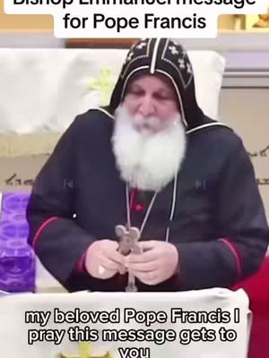 The cover image shows a man, presumably Bishop Mar Mari Emmanuel, seated and holding a cross. He is wearing a dark robe with red accents and a black hood with white trim and patterns. He has a long white beard. Text overlays at the top says "Bishop Emmanuel message for Pope Francis". At the bottom "my beloved Pope Francis I pray this message gets to you"