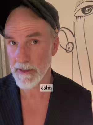 A man with a gray beard and a hat is centered in the frame, with a black suit jacket and a simple line drawing on the wall behind him. The text overlay reads "calm".
