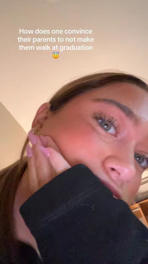 A close-up selfie featuring a young woman with fair skin, light eyes, and pink nail polish. She is holding her hand up to her face, with the overlayed text asking how to convince parents not to have them walk at graduation.
