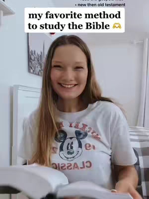 A young woman with long blonde hair smiles at the camera, holding an open book, with a white t-shirt that has the Mickey Mouse character on it, and an overlaid rectangular text banner in white the top.